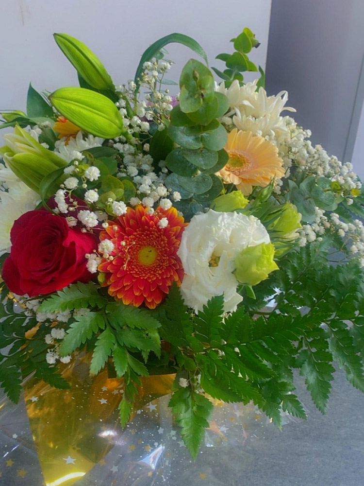Bouquet de fleurs Champêtre Évasion, une création florale d'Iris Garden. Un mélange harmonieux de roses rouges, de gerberas éclatants et de lys délicats, agrémenté de verdure luxuriante et de gypsophile vaporeux. Parfait pour illuminer toute occasion !
