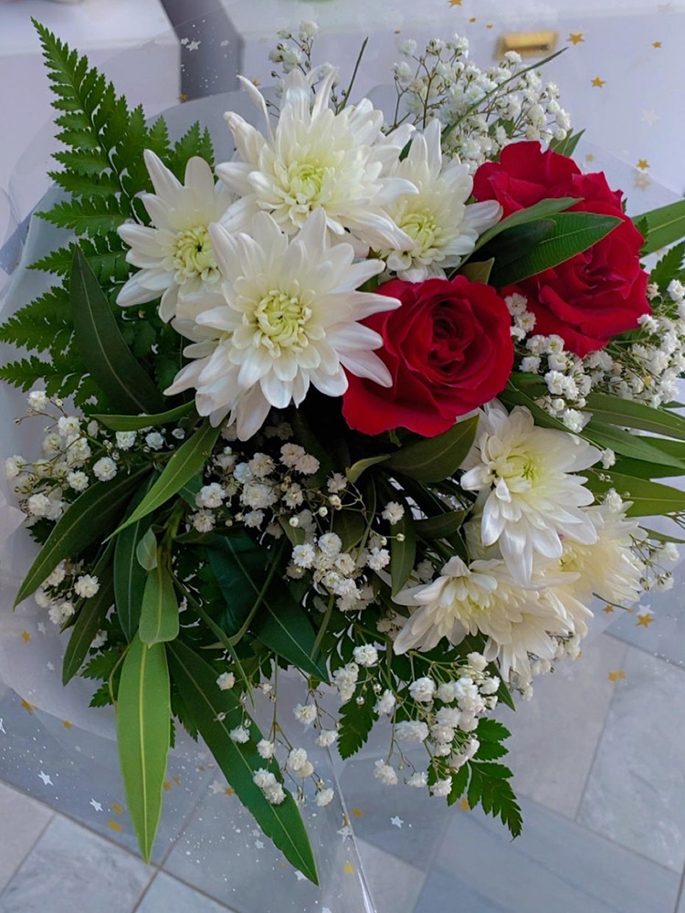 Bouquet Fleur d'amour, une création florale d'Iris Garden. Un arrangement délicat de roses rouges, de chrysanthèmes blancs et de gypsophile, rehaussé de verdure fraîche. Parfait pour exprimer vos sentiments avec élégance