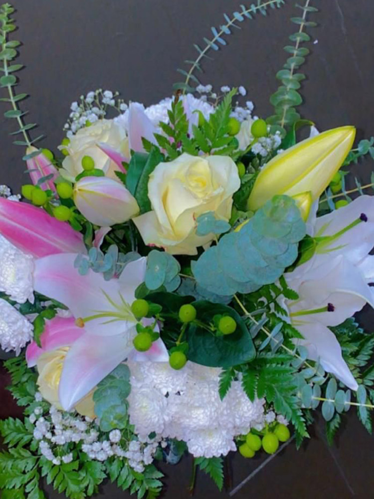 Composition Pétales d'Eté de lys blancs, roses claires et eucalyptus sur lit de gypsophile