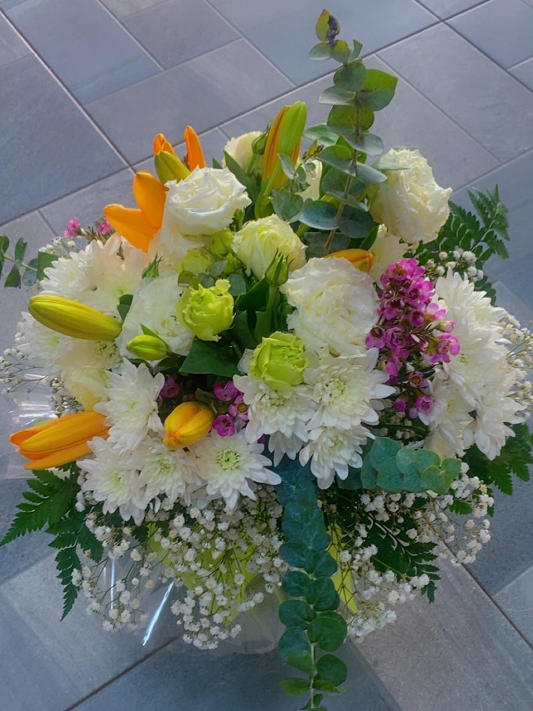 Alliance fleurie, Composition mêlant roses blanches, chrysanthèmes, lys orangés et touches roses