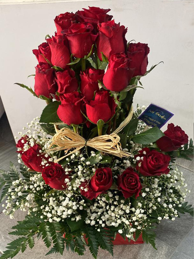 Amour sincère, arrangement de roses rouges passionnées et gypsophile blanc, lié d'un ruban raffiné de raphia.