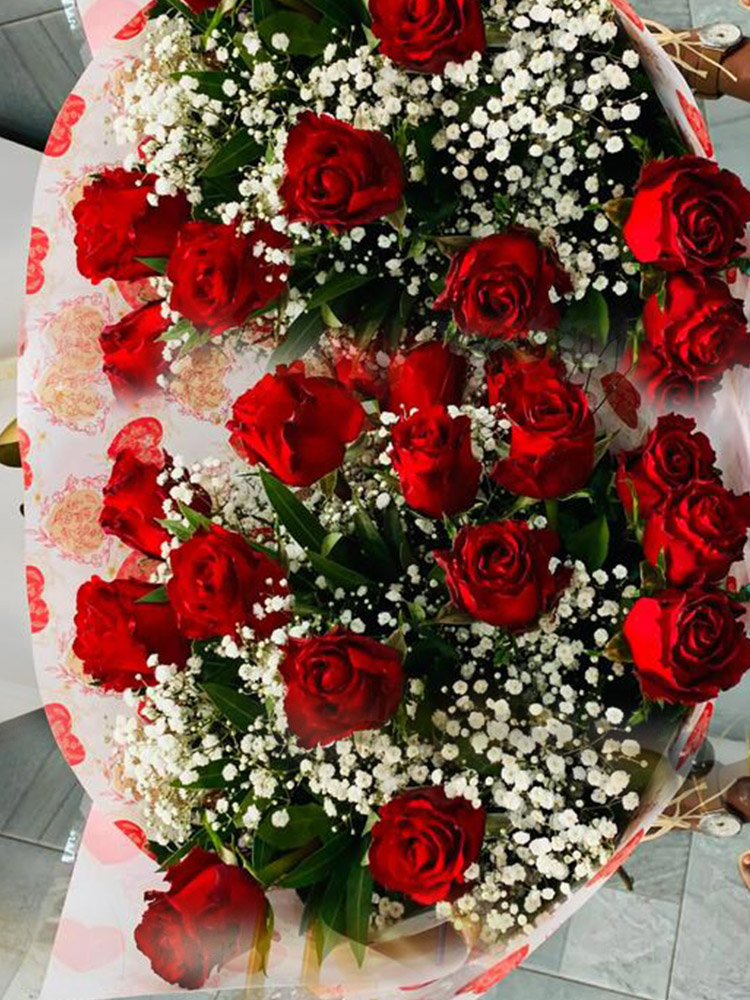 Tendresse, un bouquet de roses rouges éclatantes et gypsophile blanc délicat dans un emballage.