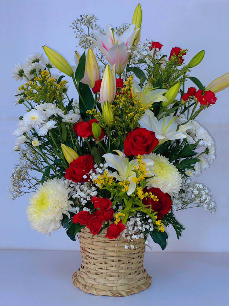 Bouquet de fleurs variées (roses rouges, lys blancs, chrysanthèmes) dans panier en osier - iris garden dakar