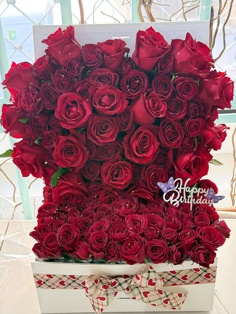 Larmes de Rosée — élégante biche florale d'Iris Garden Dakar, avec des roses rouges de luxe dans un vase