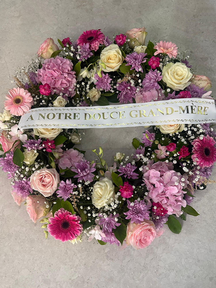 Couronne florale “Teranga d’Or” — composée de roses dorées et orangées et de gerberas lumineux.