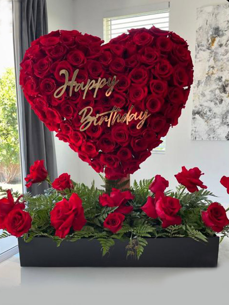 Cœur géant de roses rouges avec message Happy Birthday sur base noire fleurie